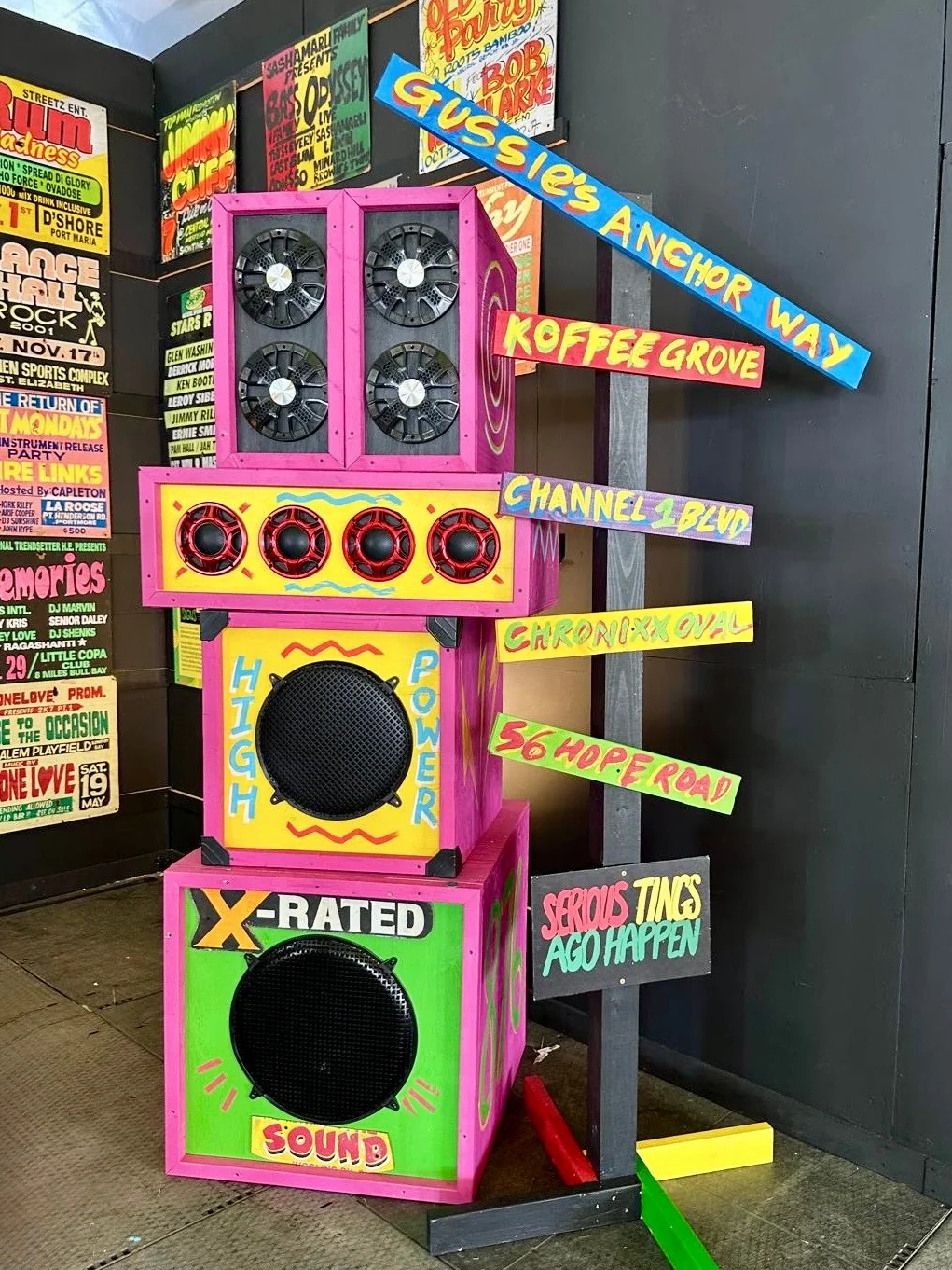 A hand-painted Jamaican sound system tower stacked with speakers and signs